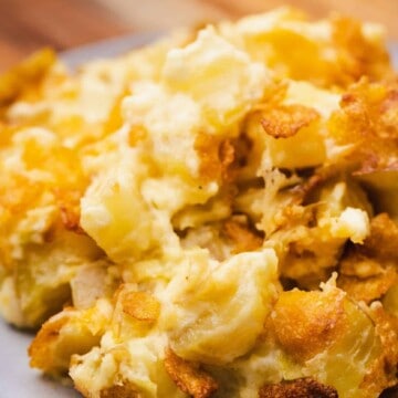A serving of Funeral Potatoes sits on a plate ready to enjoy.