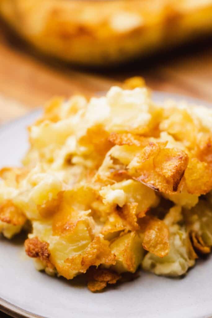 A serving of Funeral Potatoes sits on a plate ready to enjoy.