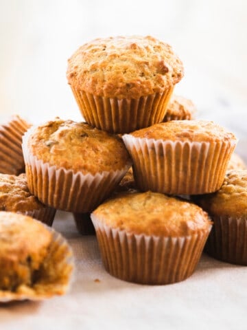 Nine bran muffins sit stacked on a surface ready to eat.