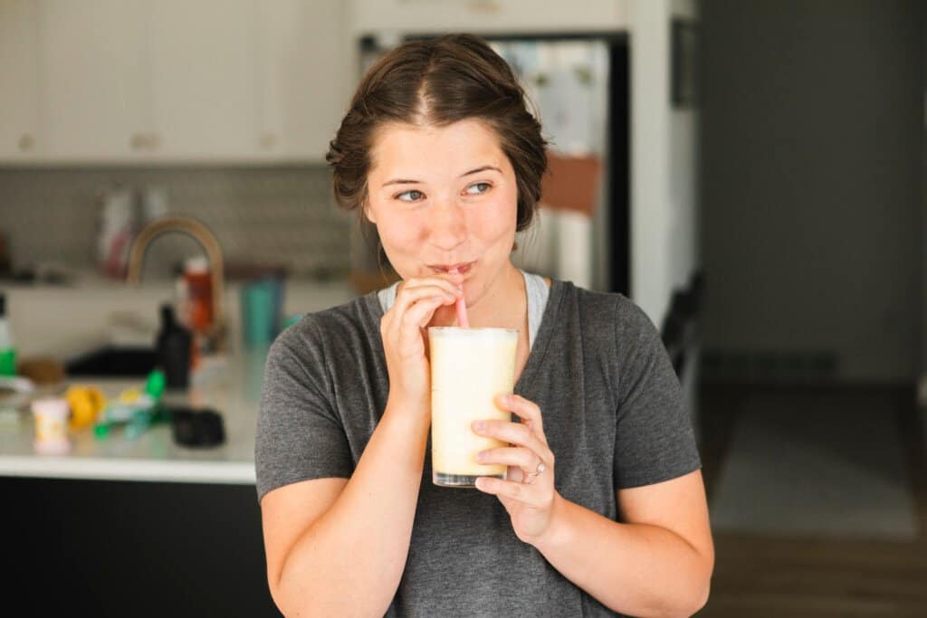 Ashley, a woman, drinks her Orange Julius from a glass with a straw.
