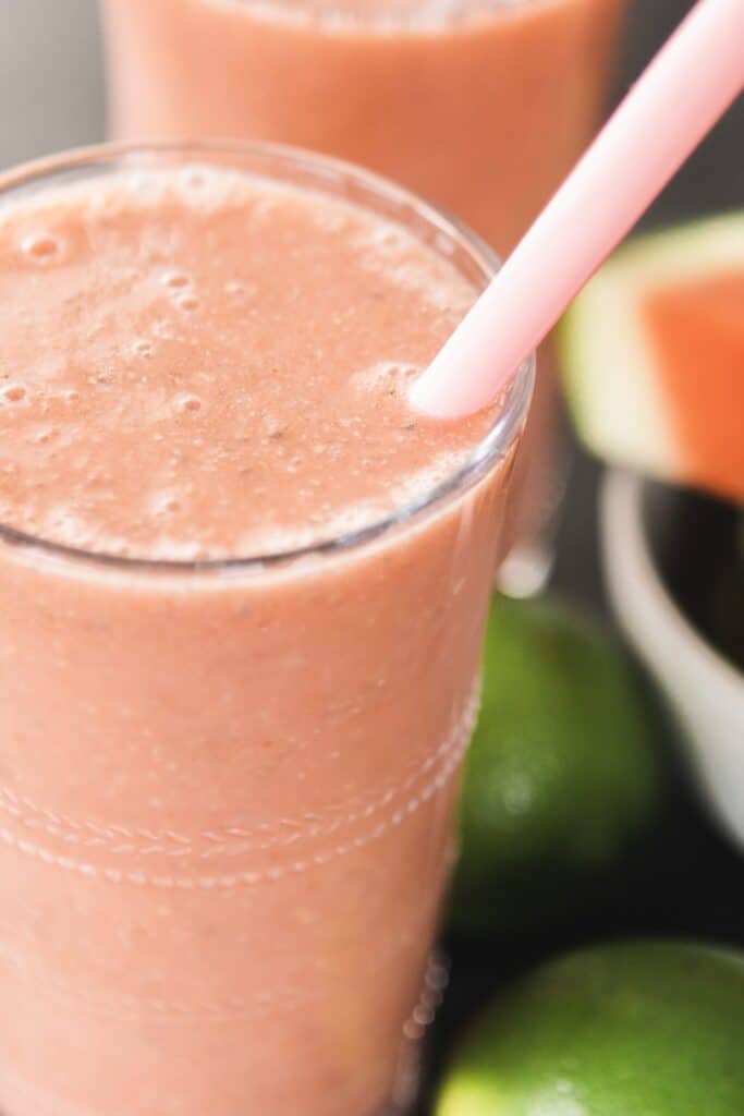 Glass of Watermelon Smoothie is full, ready to enjoy with a pink silicone straw.