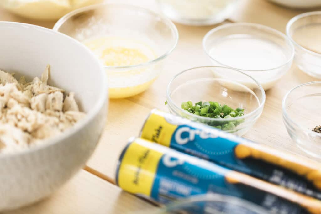 Ingredients for chicken crescents sit on a counter in individual glass bowls ready to be combined. 