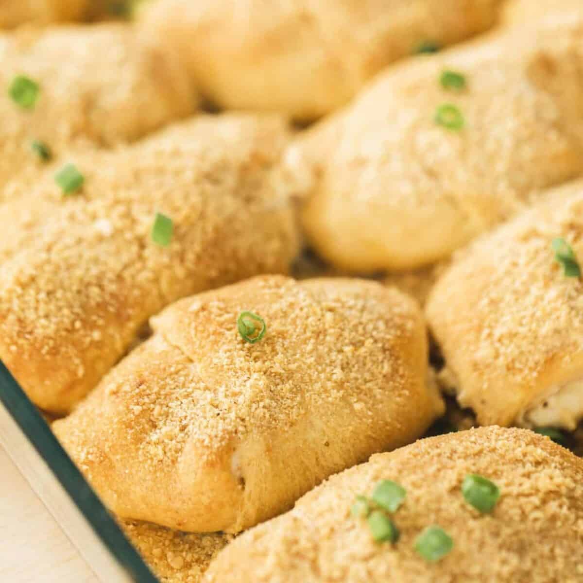 Chicken Crescent Roll Ups sit in a casserole dish, garnished and ready to eat.