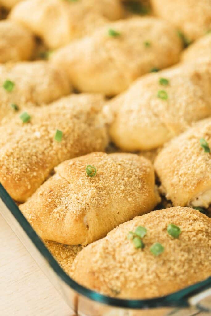 Chicken Crescent Roll Ups sit in a casserole dish, garnished and ready to eat.