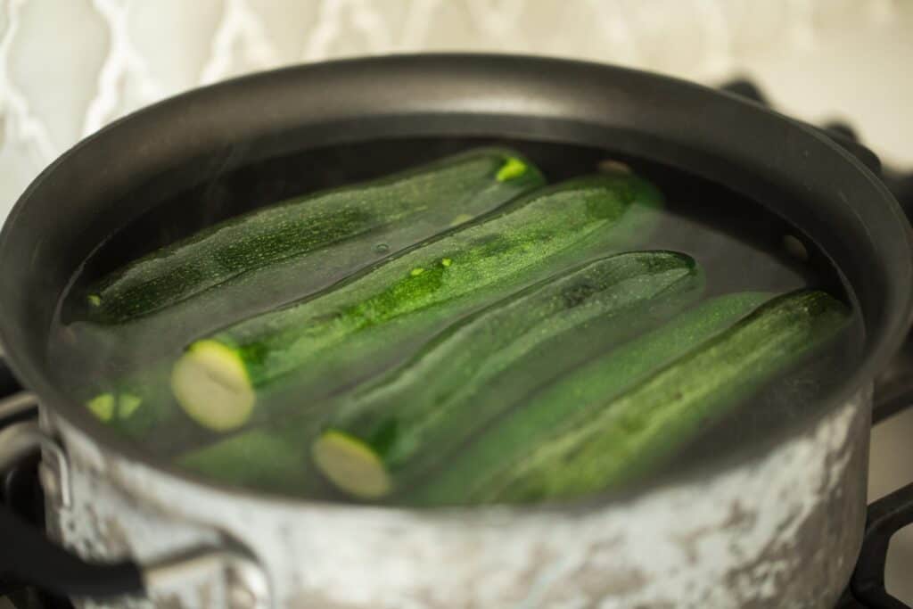 In a large pot sits zucchini ready to be blanched.