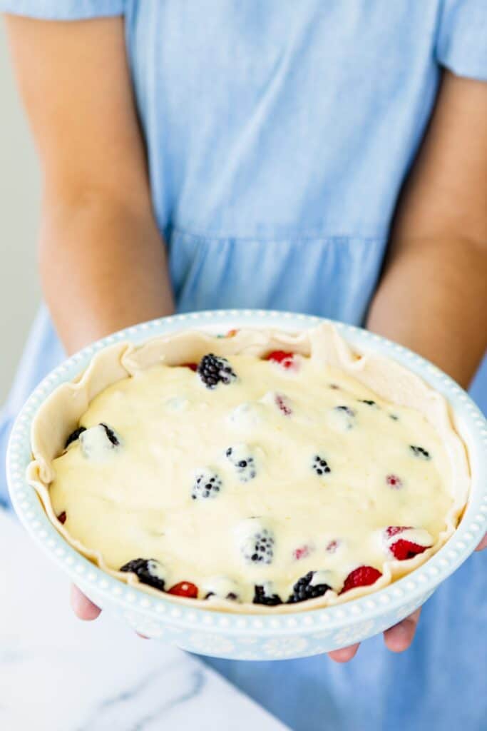 Custard filling surrounds the vibrant berries in the prepared pie tin.