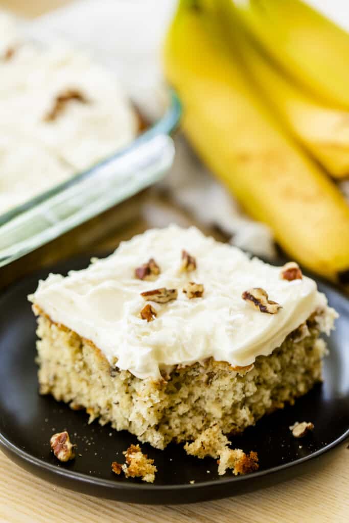 Piece of banana cake sits on a plate, garnished and ready to enjoy.