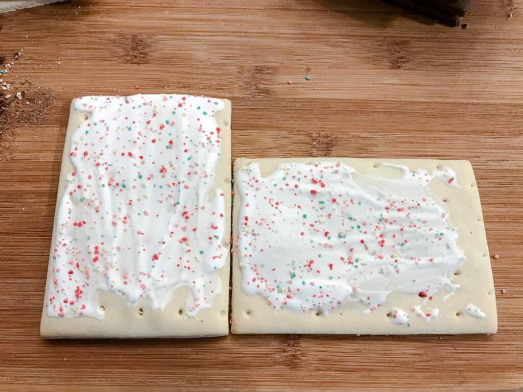 Two strawberry pop tarts sit next to one another ready to be cut for house making.