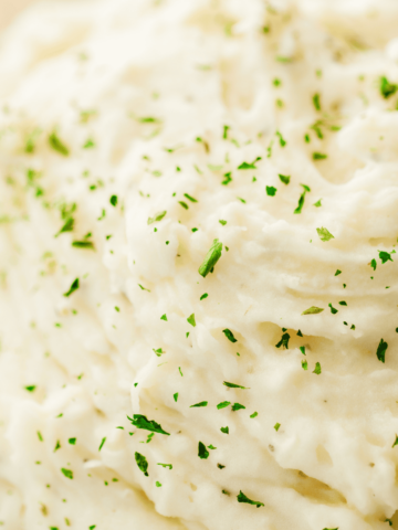 Fluffy and silky mashed potatoes are topped with fresh parsley.