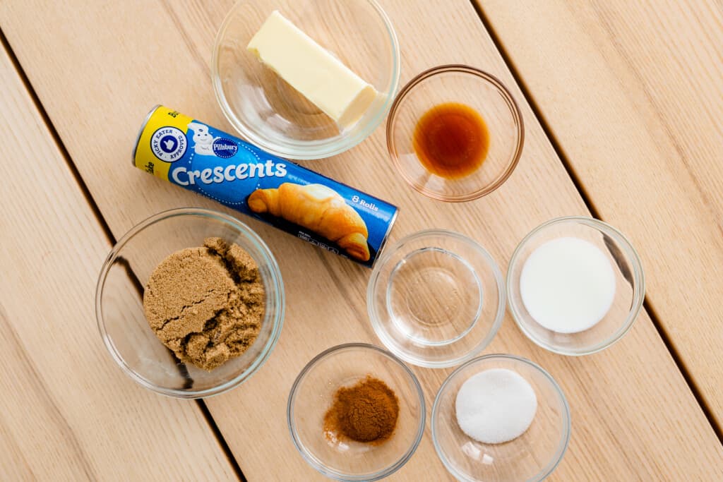 All the ingredients for caramel rolls sit out in glass bowls on top of a table ready to be combined to make a delicious Christmas morning breakfast.