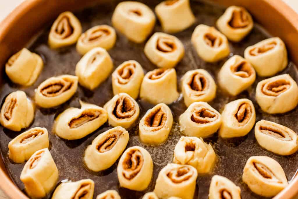 Each mini cinnamon roll sits in the syrup filled pie dish ready to bake.