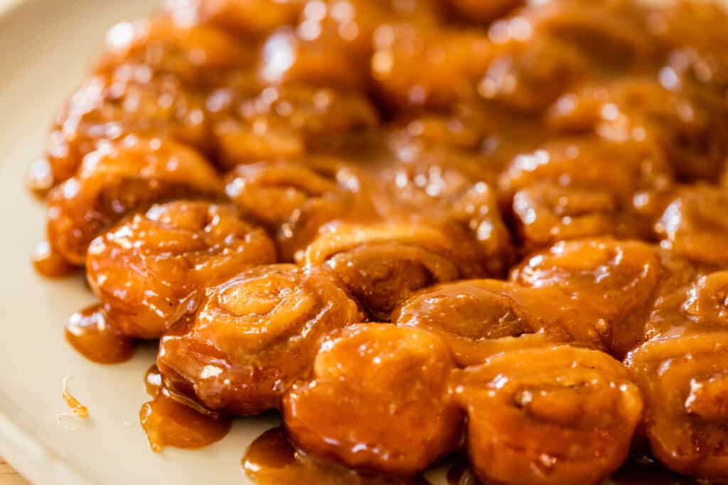 Ooey-gooey caramel rolls sit on a serving plate ready to be eaten and enjoyed on Christmas morning.