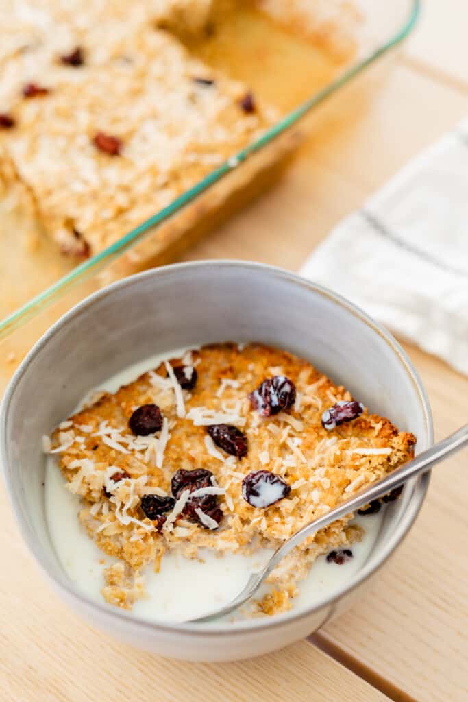 Baked Oatmeal Casserole sits in a bowl with milk poured over the top.