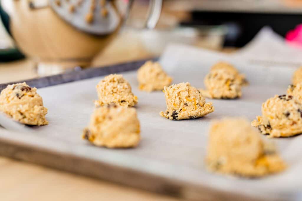 Balls of sunshine cookie dough are spaced on a cookie sheet ready to go into a hot oven to bake.