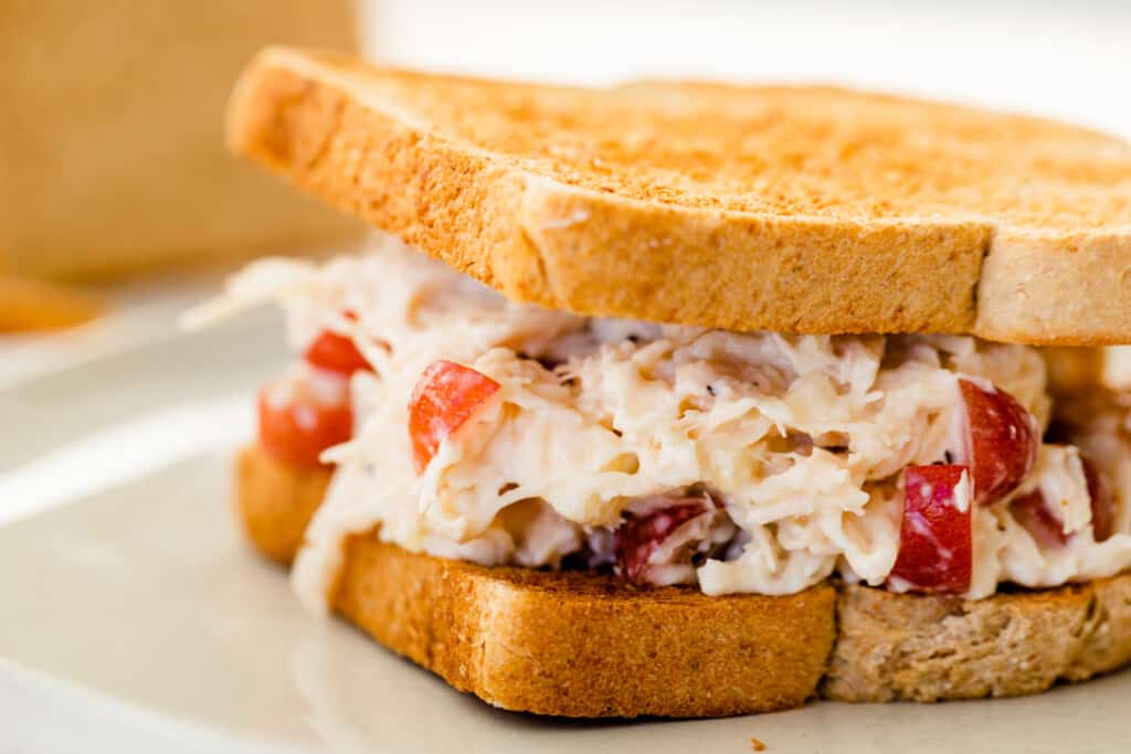 Chicken salad on toasted whole wheat bread is served on a plate.