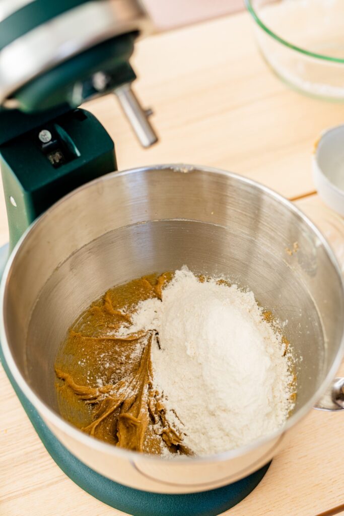 Creamed butter and sugar sit in the bottom of a kitchen aid mixer. Dry ingredients sit on the top ready to be mixed in.