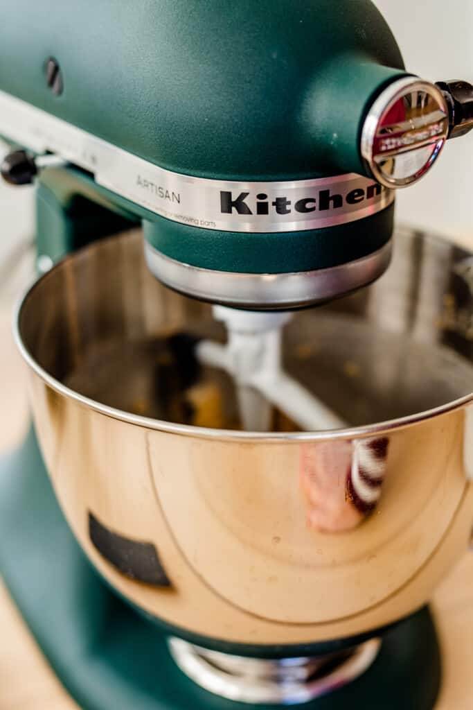 Kitchen aid mixer sits on the counter mixing dough ingredients.