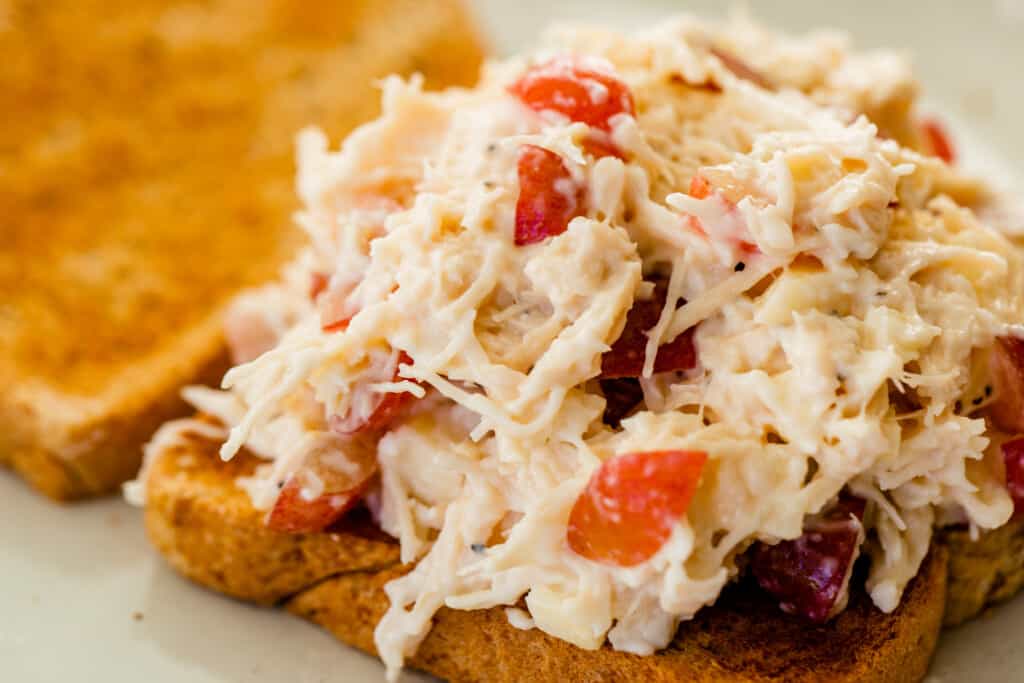Large scoop of chicken salad sits on top of a toasted piece of bread.