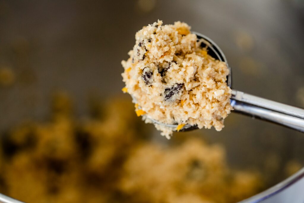 A scoop of cookie dough sits inside a scoop ready to be put on a baking sheet.
