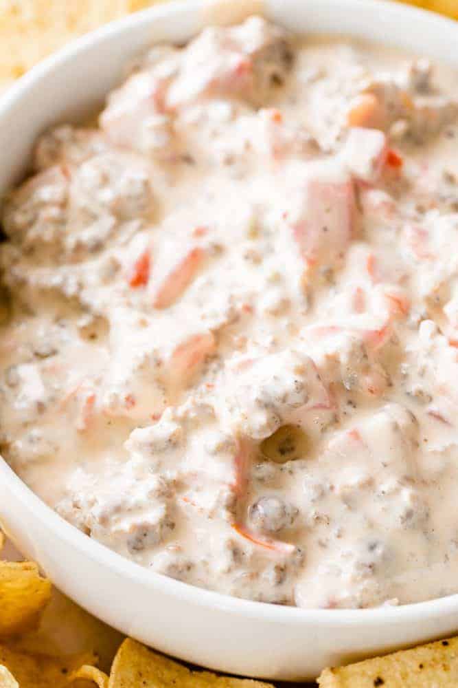 Bowl of sausage rotel dip with super creamy texture sits on a table surrounded by tortilla chips ready to enjoy.