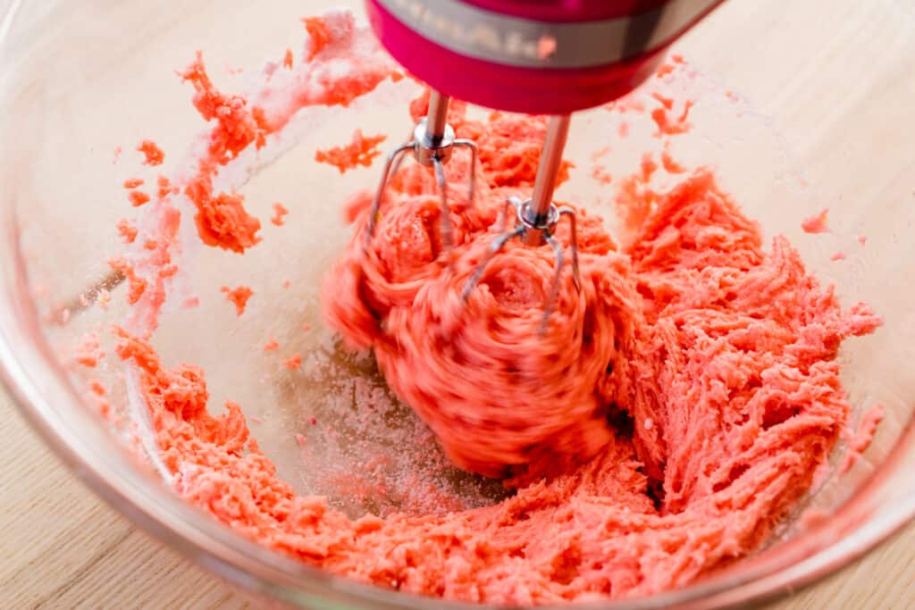 Hand mixer beats together cookie dough mixture into a dough.