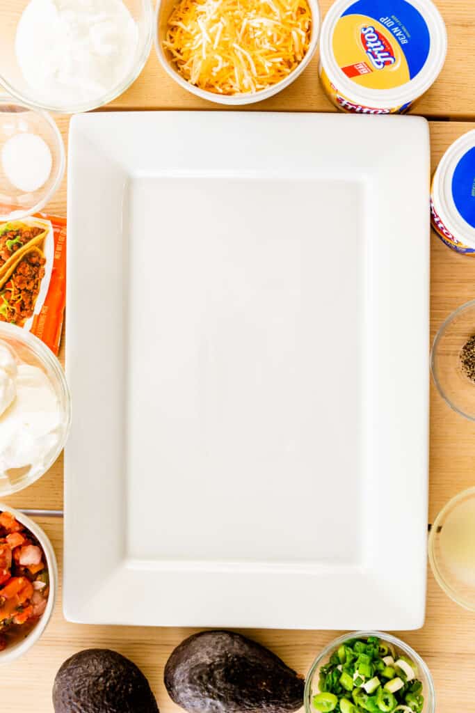 Ingredients for dip are placed around a white serving platter.