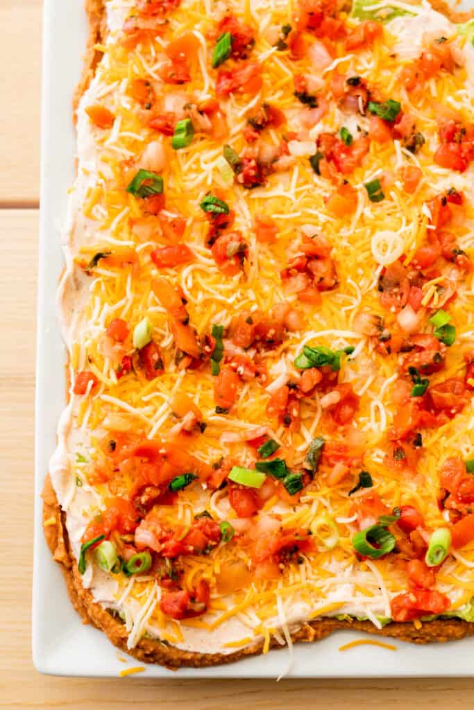 Six layers of bean dip are spread and scattered across a platter, layered on top of each other.