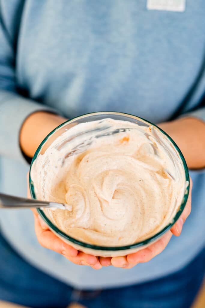 The sour cream mixture is stirred together in a glass bowl in Ashley's hands.