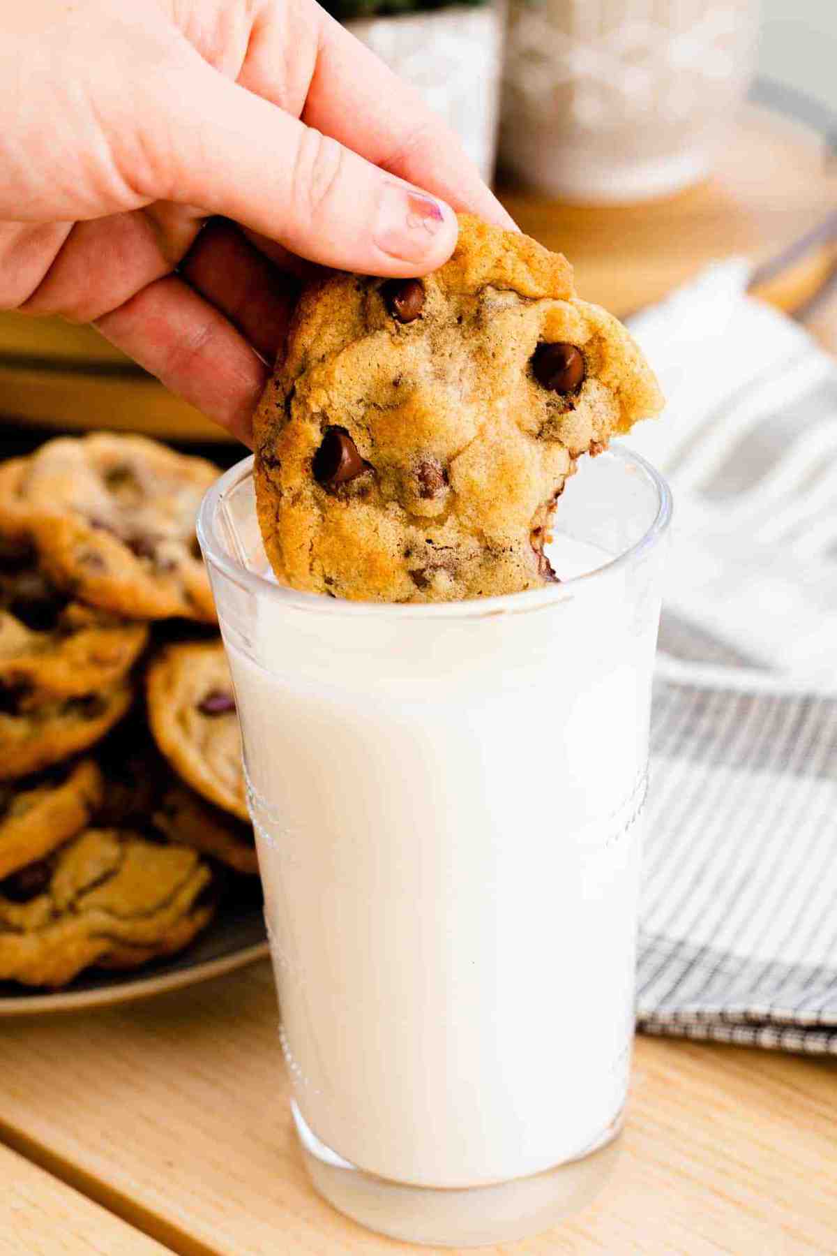 Ashley dunks a fresh chocolate chip cookie in a tall glass of cold milk.