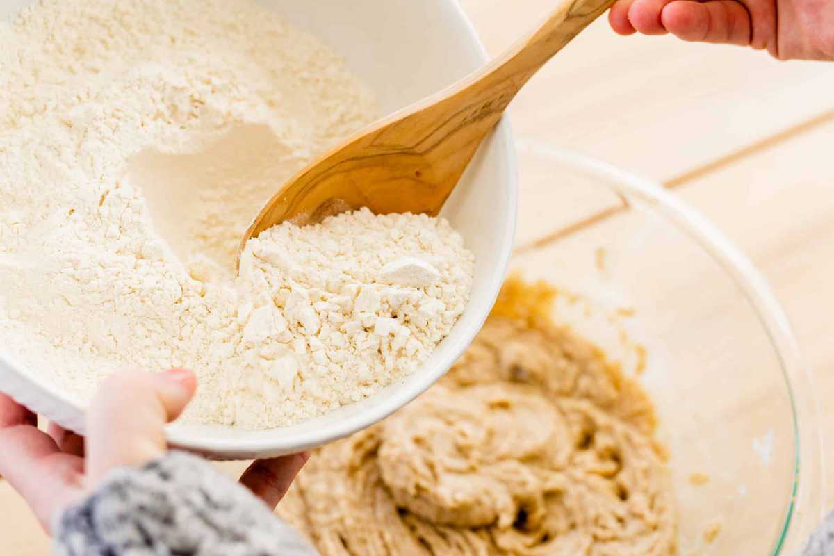 Ashley slowly adds dry ingredients to a bowl of wet ingredients.