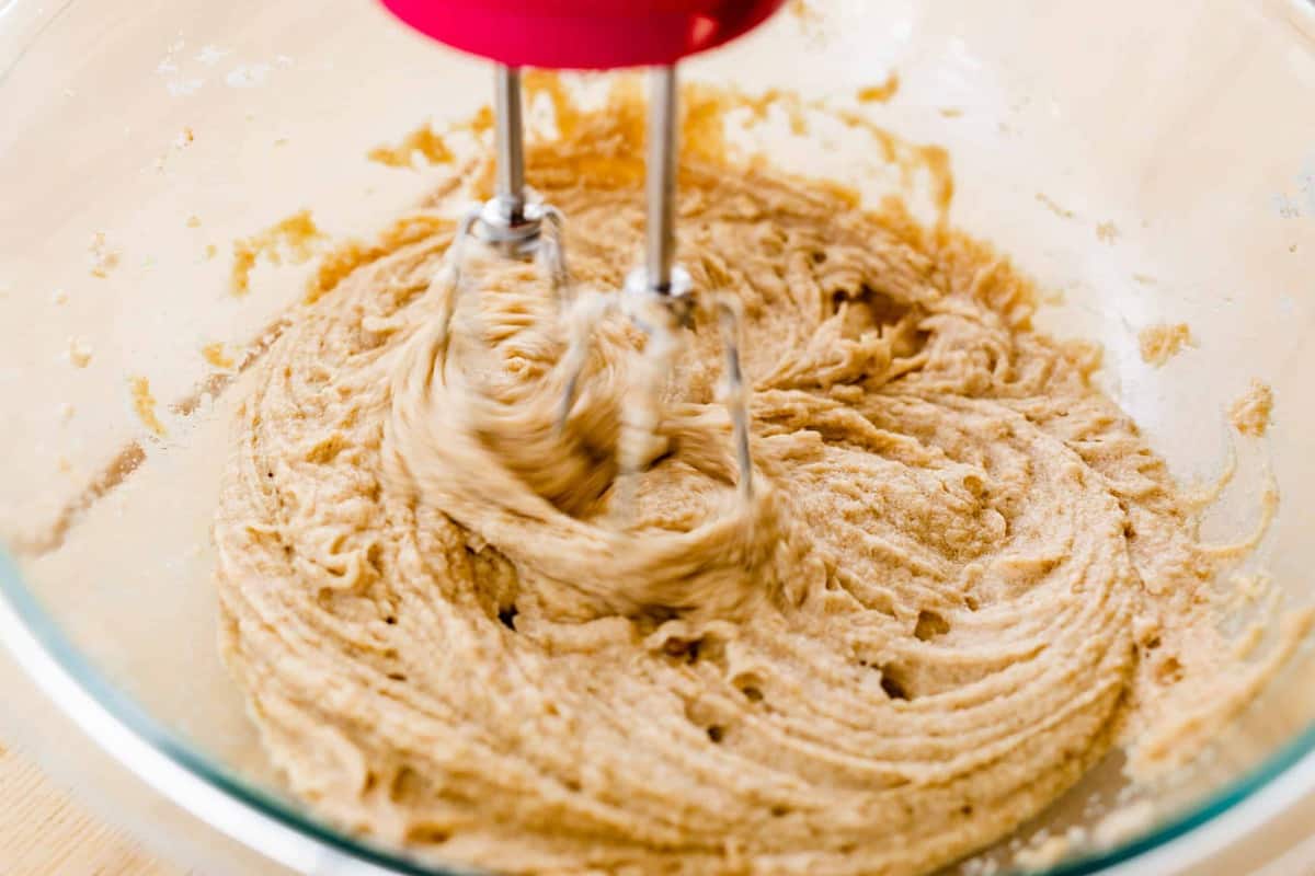 A hand mixer blends all of the wet ingredients for cookies.