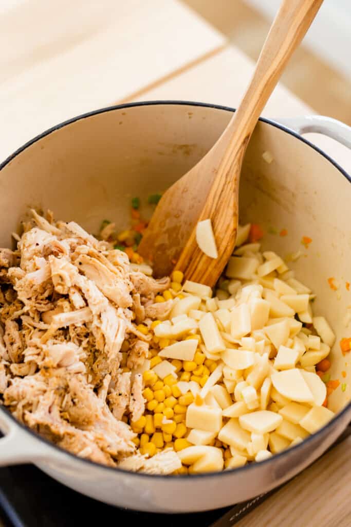 Shredded chicken, corn and diced potatoes have been added to the pot.