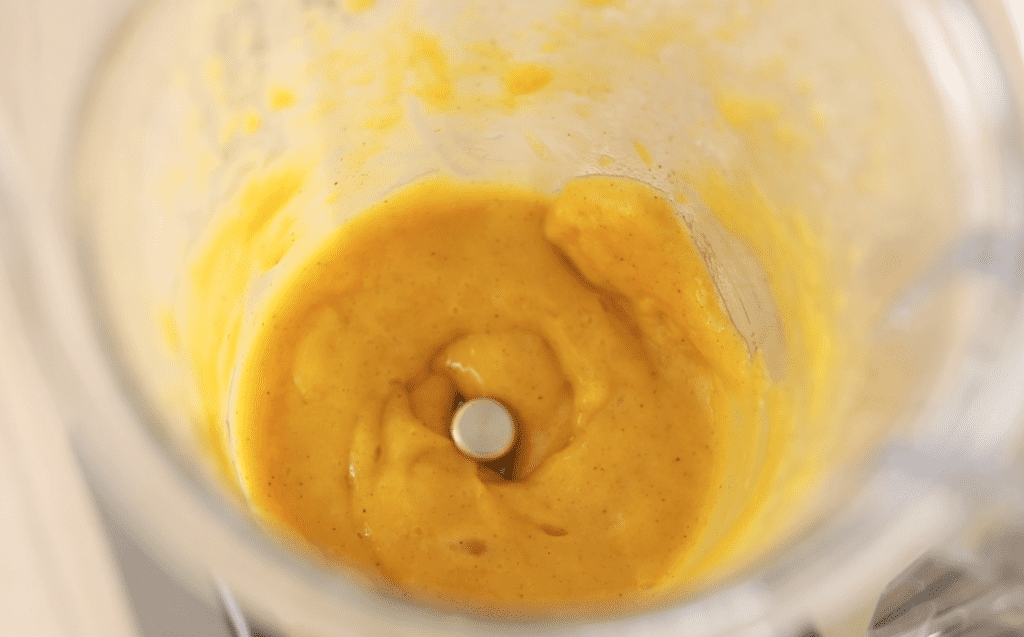 Creamy Cinnamon Mango Dressing sits in the bottom of a blender cup.