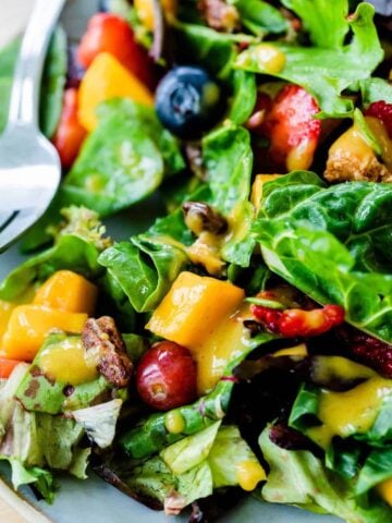 A serving of Mango Berry Salad on a plate, drizzled with creamy Cinnamon Mango Dressing, ready to eat!