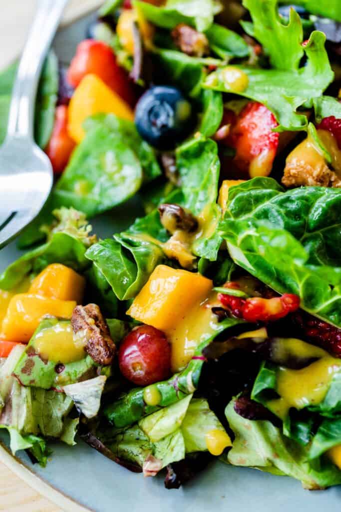 A serving of Mango Berry Salad on a plate, drizzled with creamy Cinnamon Mango Dressing, ready to eat!