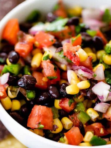 Bean and corn salsa sits in a serving bowl alongside blue corn chips.