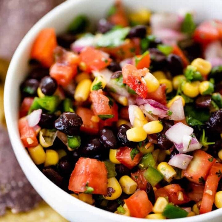 Bean and corn salsa sits in a serving bowl alongside blue corn chips.