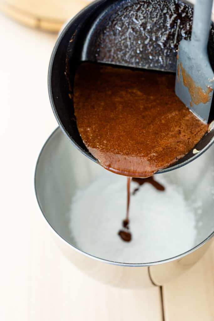 Melted chocolate mixture is added to a bowl of dry ingredients ready to combine for cake batter.
