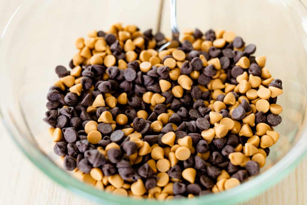 Chocolate and butterscotch chips are combined in a larger glass bowl and mixed together.