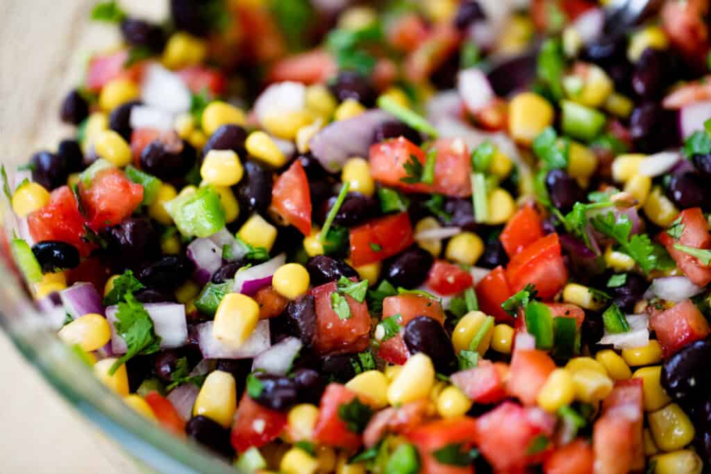 A large glass bowl is filled with Cowboy Caviar ready to serve.