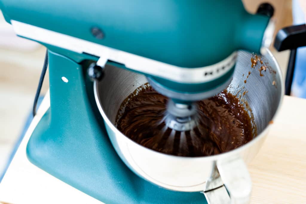 Kitchen Aid mixer is turned on and mixing chocolate cake batter.
