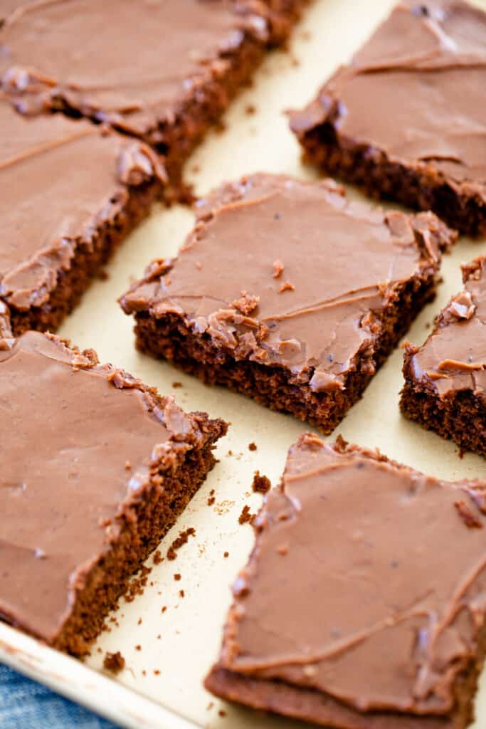 Cake is sliced into squares and sits on a sheet pan ready to serve.