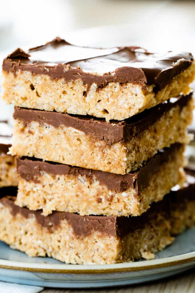 Four scotcheroo bars sit stacked on a plate.