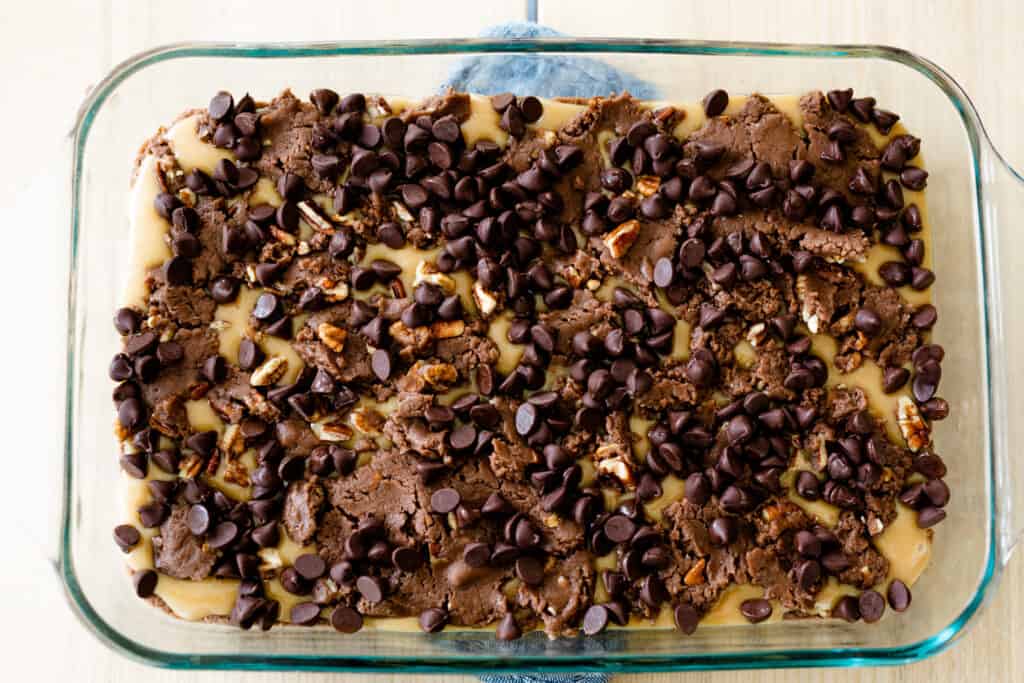 Chocolate chips are scattered across the top of the brownie dough, ready for the oven.