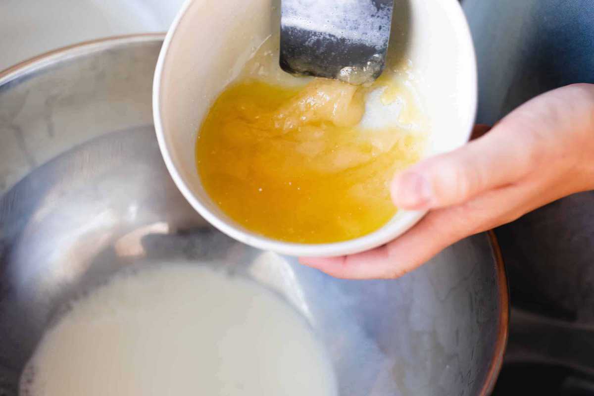 Butter, salt and sugar are combined in a white bowl, ready to pour into a bowl of heated milk.