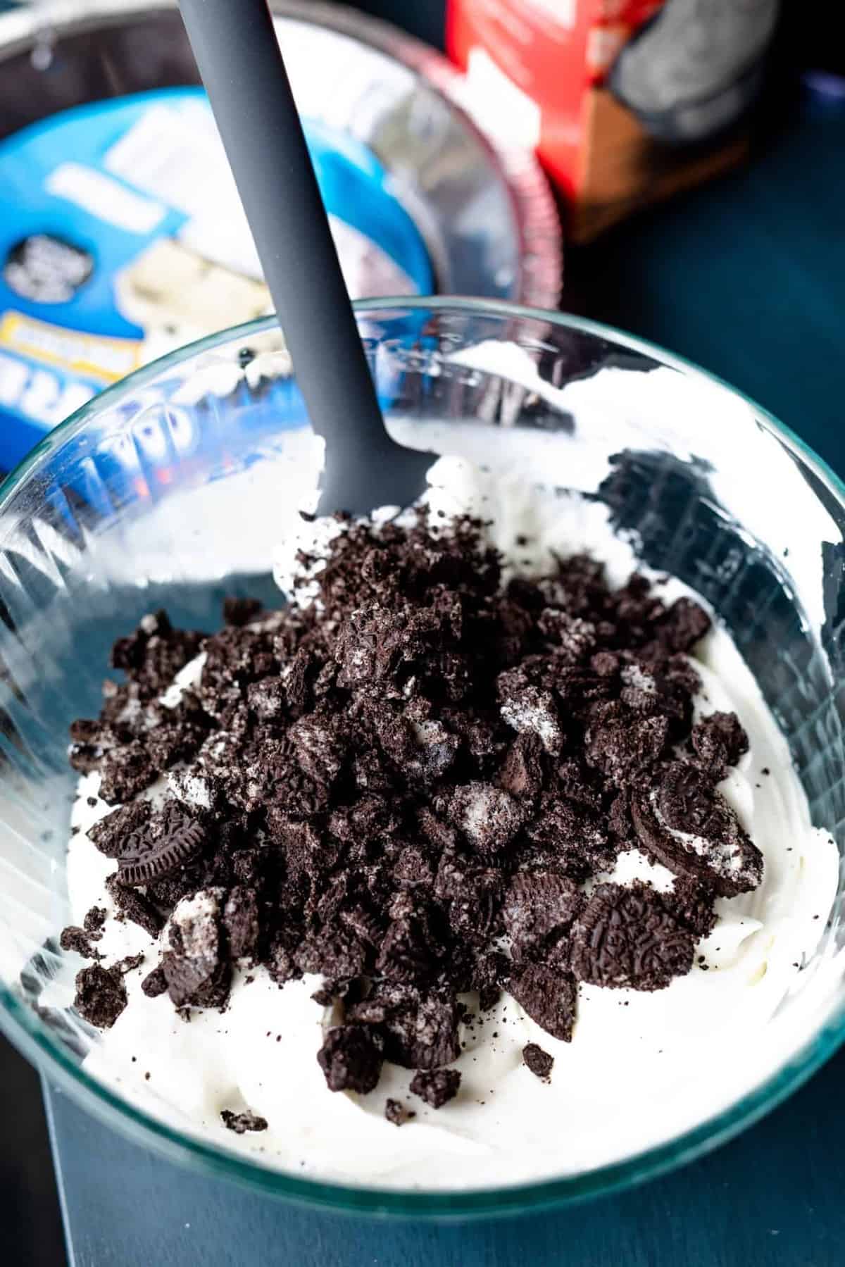 Crushed Oreo cookie chunks sit on top of a bowl of cream pie filling.