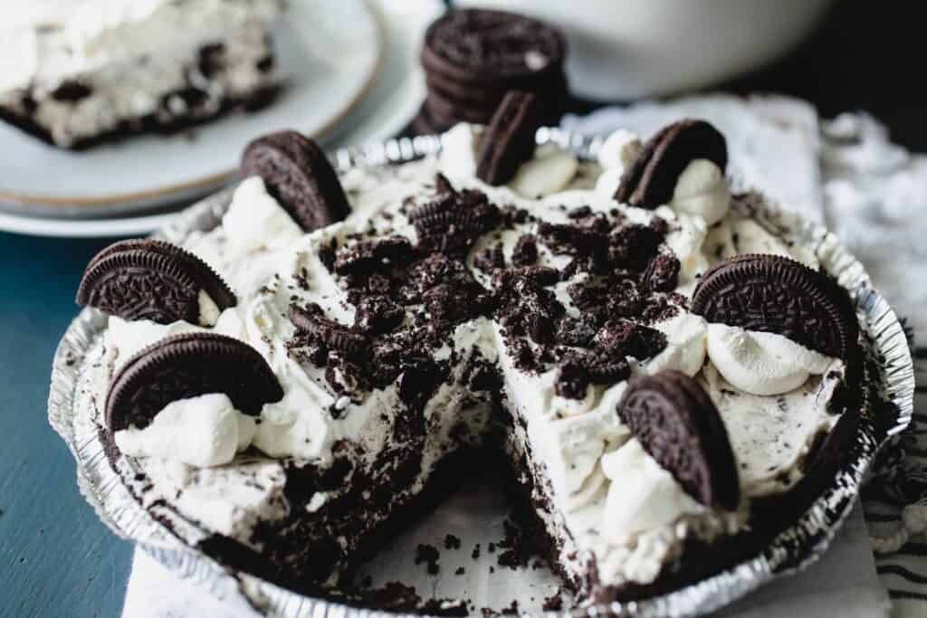 An Oreo cheesecake pie sits on the counter with a slice removed.
