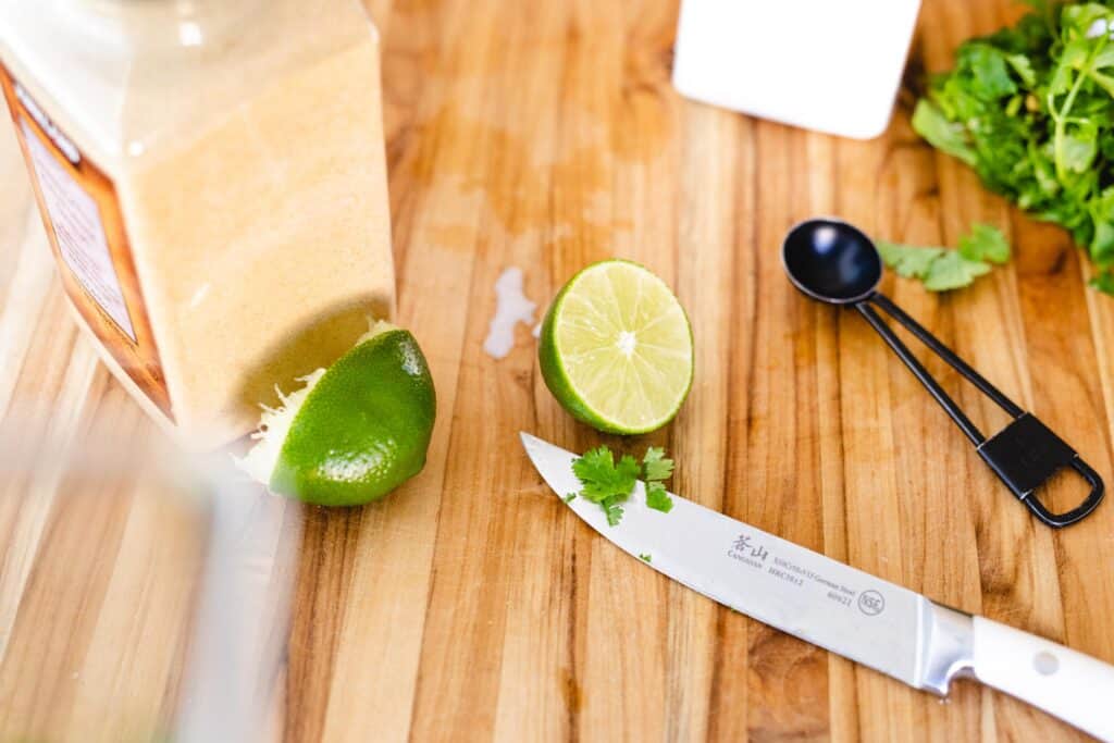 Cut in half lime sits on a board ready to be used in the recipe.