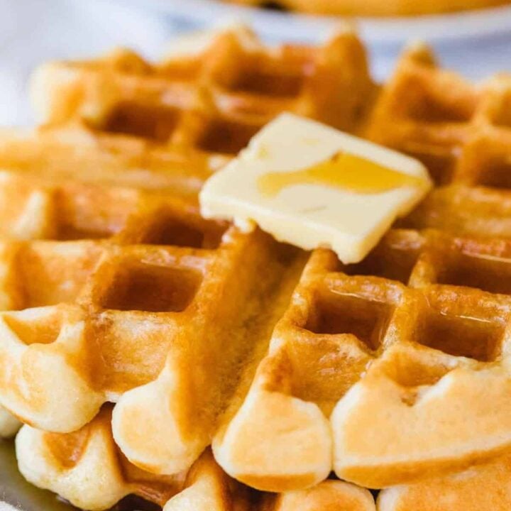 Crispy, hot waffles sit on a plate ready to be eaten.