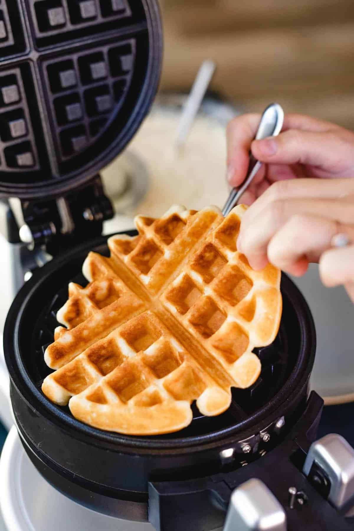 Ashley pulls a golden brown, crispy waffle off of a waffle iron.